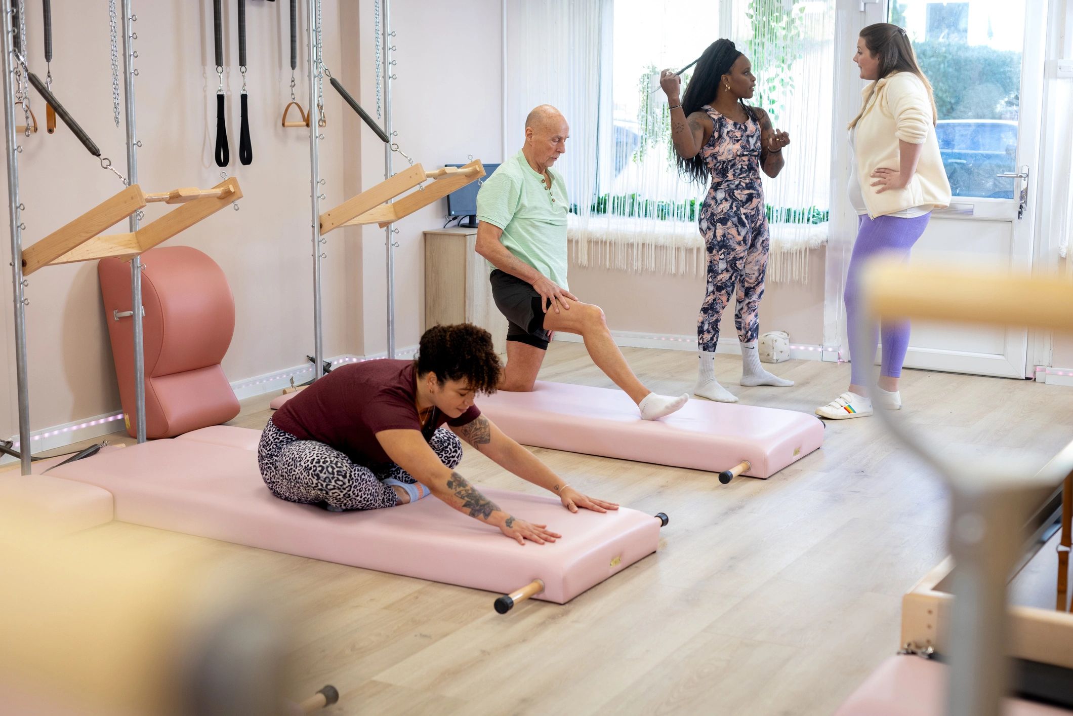 Clients training together on reformer-style equipment in a bright boutique fitness studio